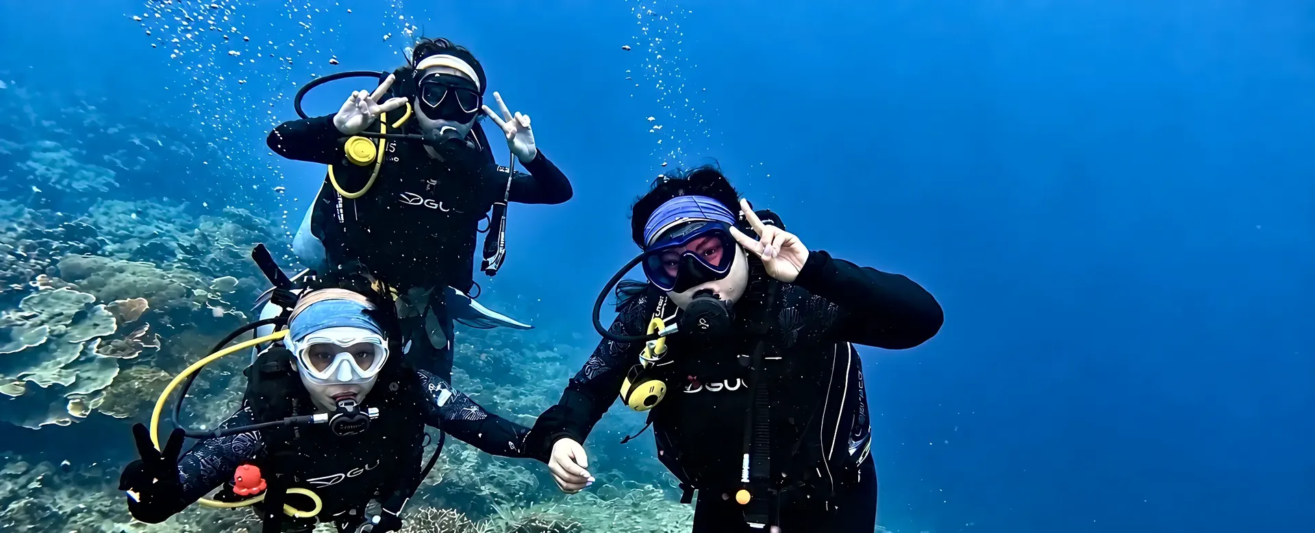 Margaretha, Brigitta and Graciella making peace signs on a reef